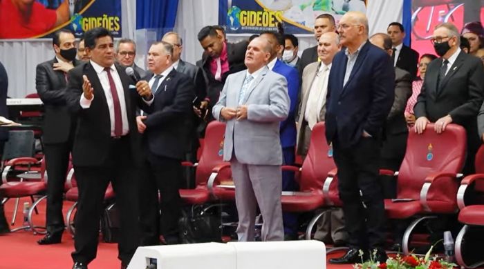 Pastor Gilmar (com o microfone) prega nos Gideões, e exalta "exemplo" do ministro Milton, à direita./Fotos Reprodução.