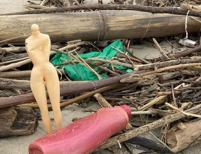 Bonecas e embalagens de plástico em meio á sujeira trazida pela maré