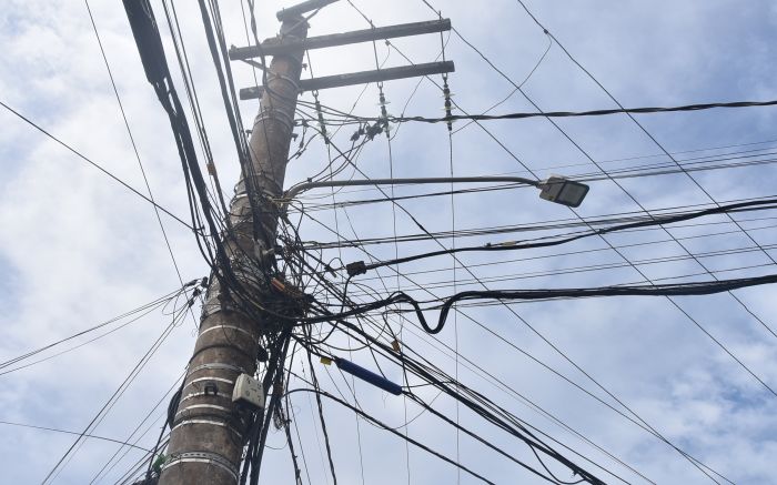 Postes têm virado um emaranhado de fios, com cabos antigos que nem são mais usados por clientes das operadoras de internet, e fiação solta na rua com risco aos pedestres(Foto: João Batista)